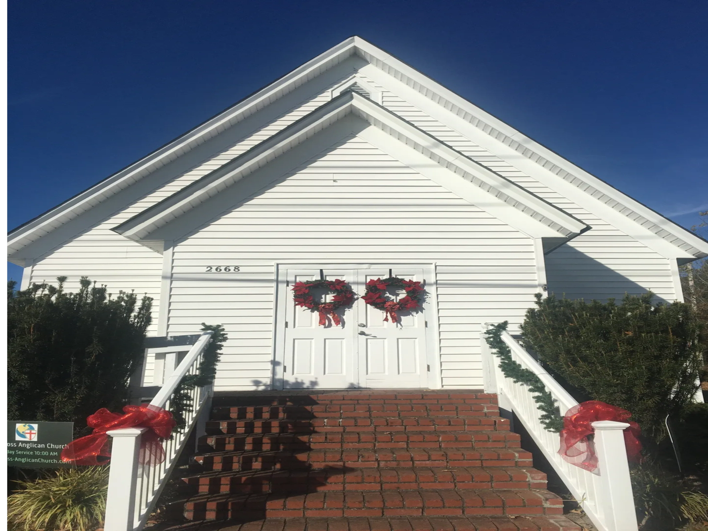The white church building and front entrance of Holy Cross at 2668 Church Street